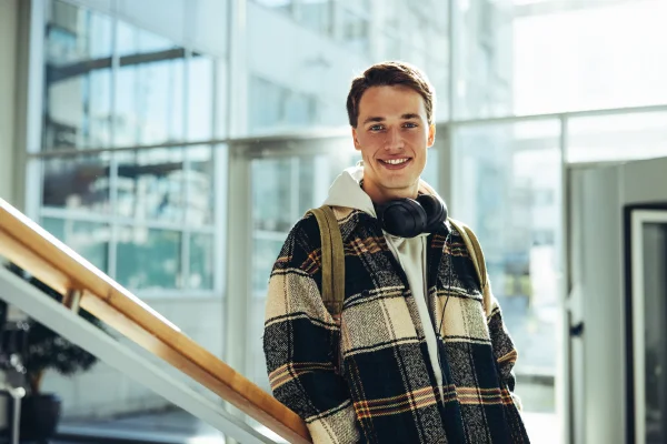 Teenager with headphones leans onto a handrail