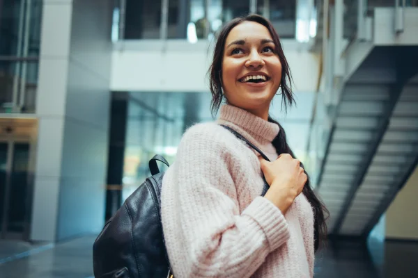 Brown haired girl with a bag smiles 